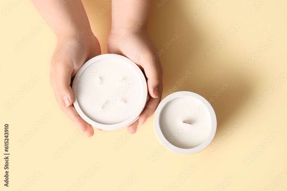 Female hands with candles on yellow background