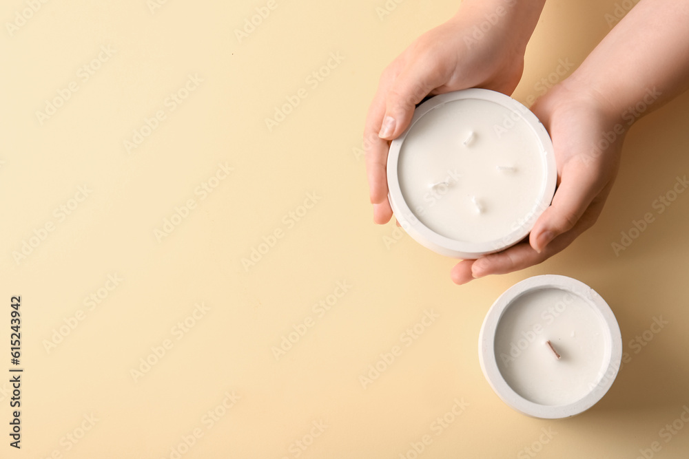 Female hands with candles on yellow background