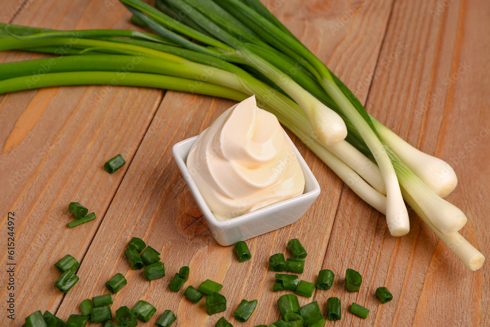 Bowl of tasty sour cream and sliced green onion on wooden background