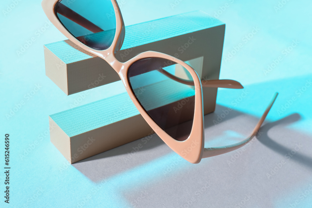 Podium with stylish sunglasses on blue background