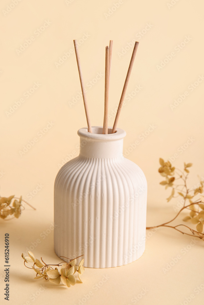 Floral reed diffuser and hydrangea flowers on beige background, closeup