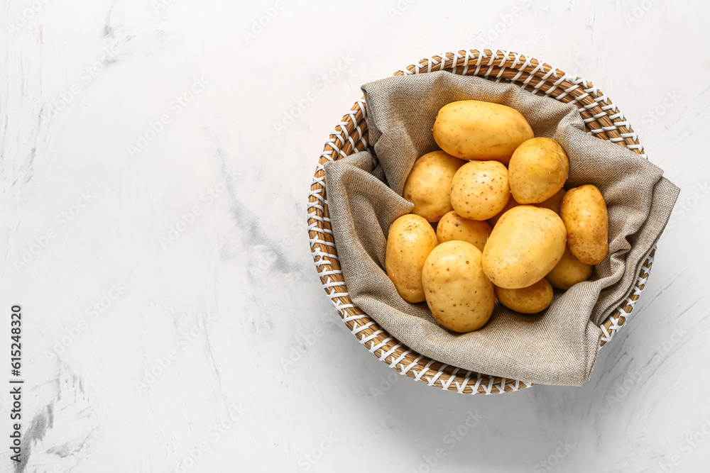 Wicker bowl with raw baby potatoes on white background