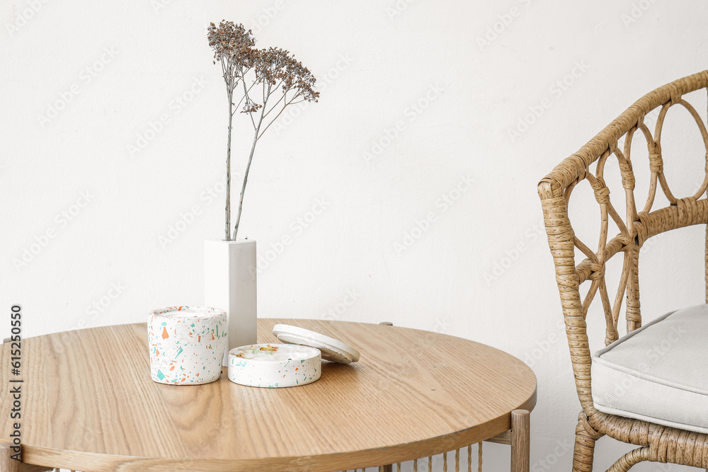 Interior of light room with flowers, candles on table and chair, closeup