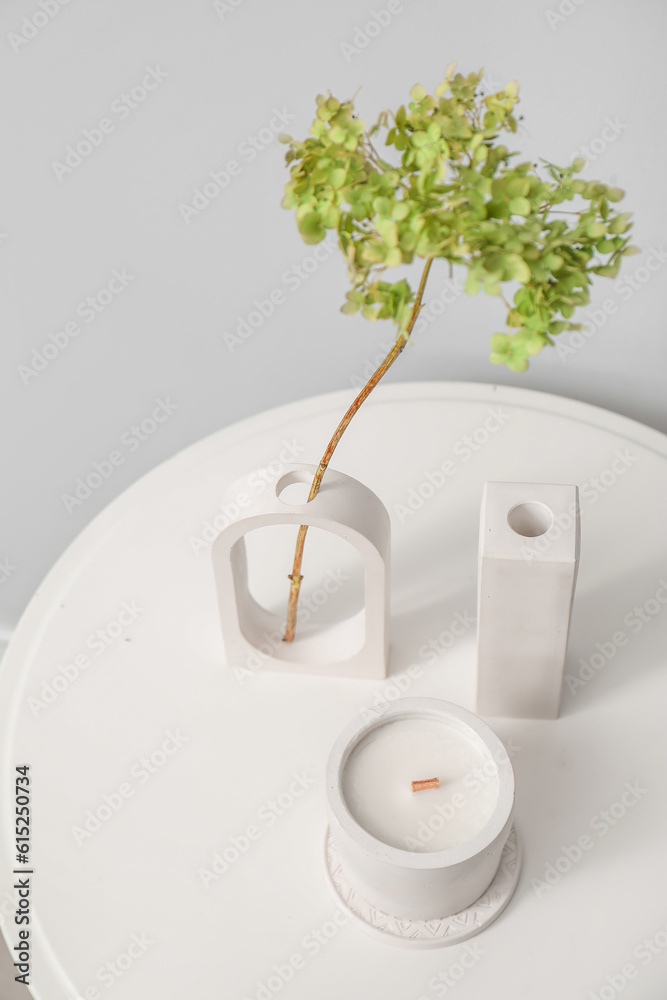 Hydrangea flowers and candle on table near light wall in room, closeup