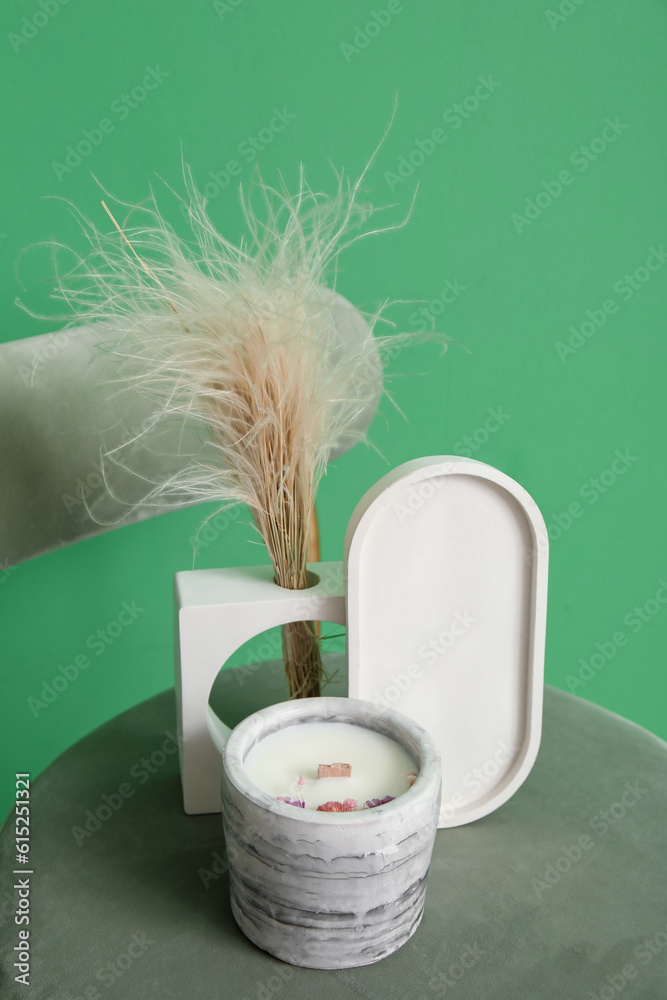 Holder with candle and pampas grass on chair near green wall in room, closeup