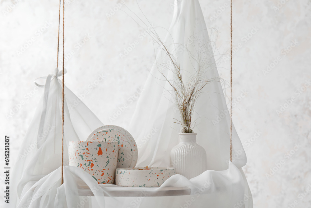 Holders with candles on hanging shelf near light wall in room, closeup