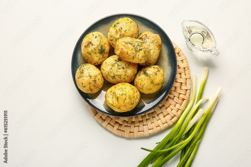 Plate of boiled baby potatoes with dill and green onion on white background