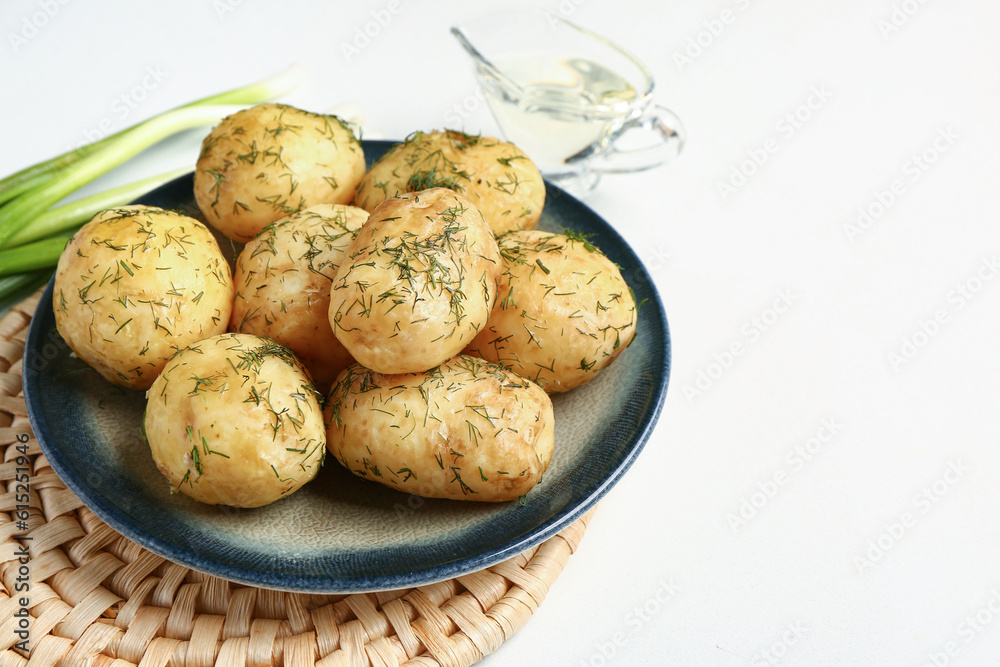 Plate of boiled baby potatoes with dill and green onion on white background