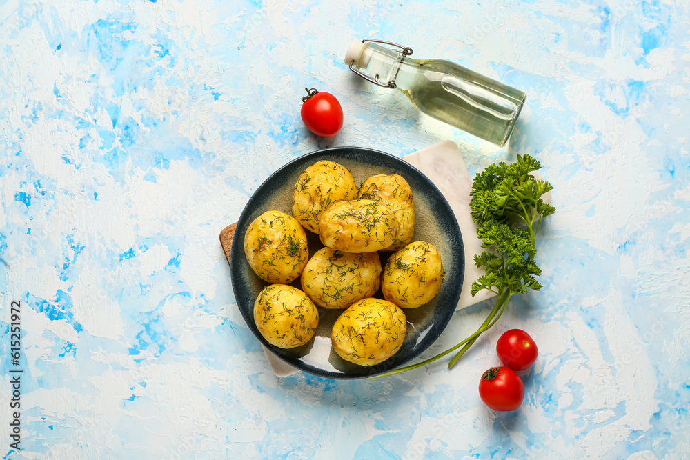 Plate of boiled baby potatoes with dill and parsley on blue background