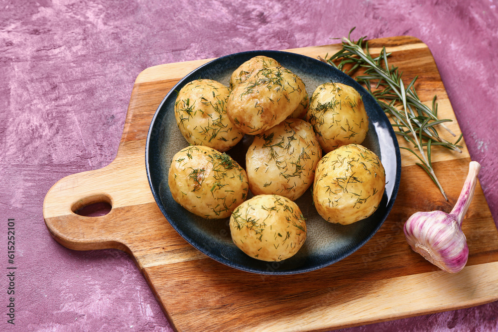 Plate of boiled baby potatoes with dill and garlic on purple background