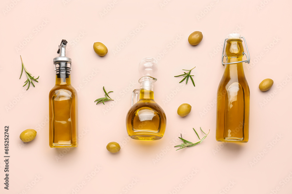 Bottles and jug of olive oil on pink background