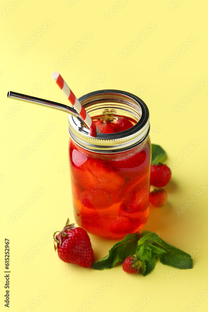 Mason jar of infused water with strawberry and mint on yellow background