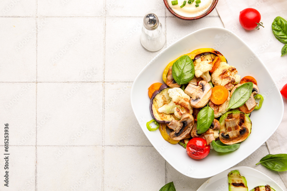 Plate with grilled vegetables and sour cream on white tile background