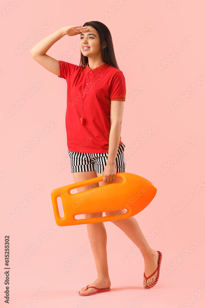 Female lifeguard with board on pink background