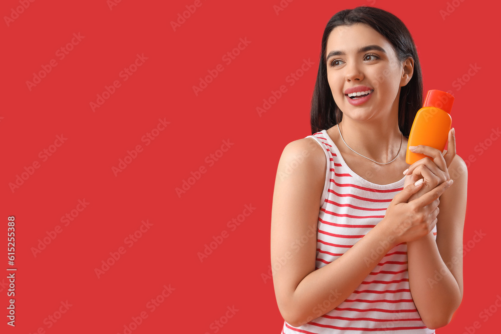 Young woman with sunscreen cream on red background