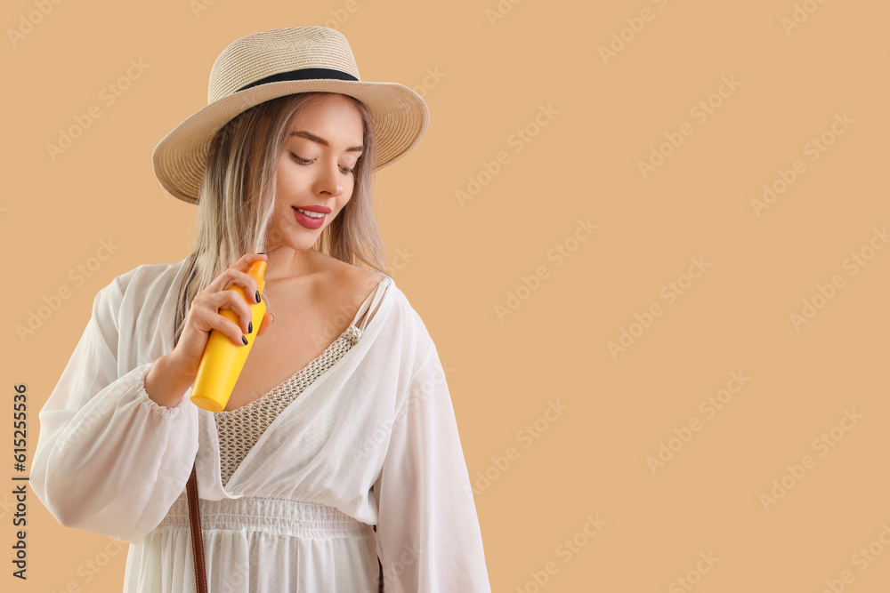 Young woman with sunscreen cream on beige background