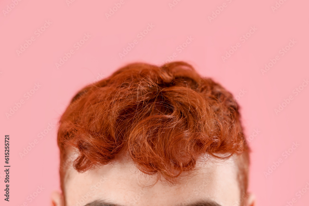 Young man with red hair on pink background, closeup