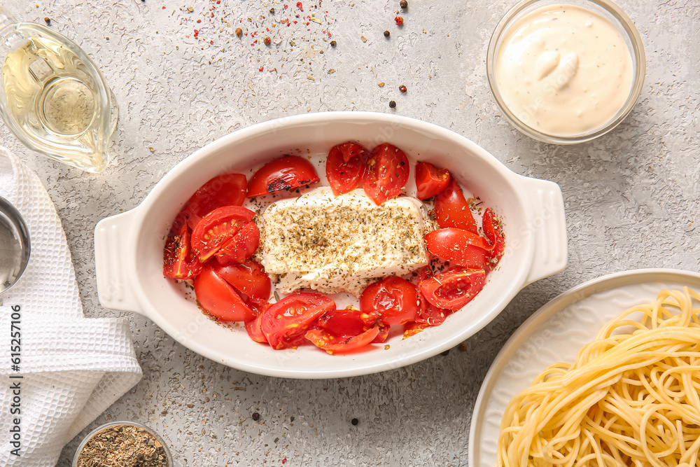 Baking dish with tasty tomatoes and feta cheese on grey background