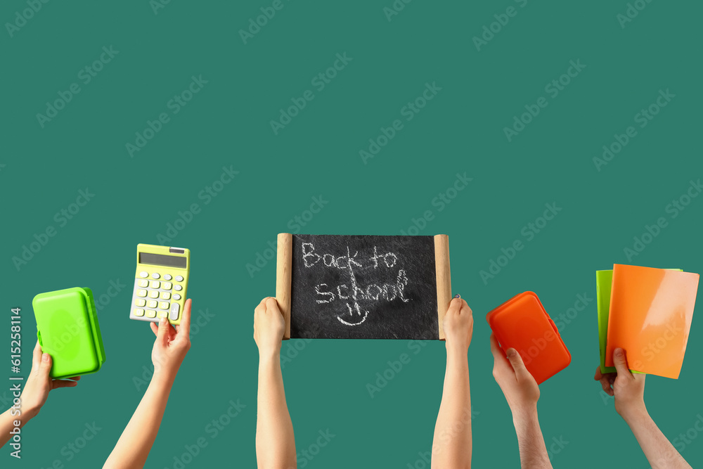 People holding chalkboard with text BACK TO SCHOOL and stationery on green background