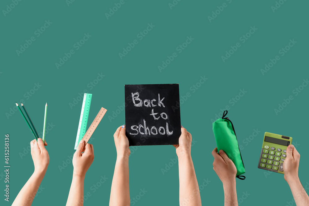 People holding chalkboard with text BACK TO SCHOOL and stationery on green background