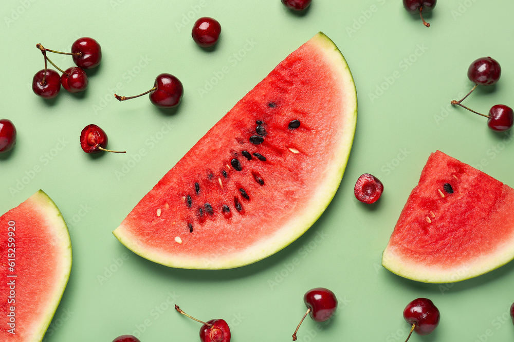 Pieces of fresh watermelon and cherries on green background