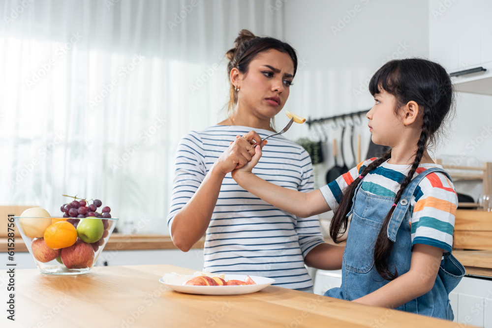 Asian mother teaching and motivate young girl child eat healthy fruit. 