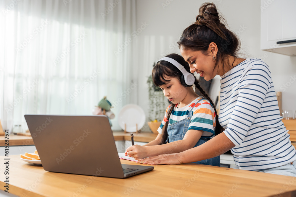 Caucasian young girl kid learning online class at home with mother. 