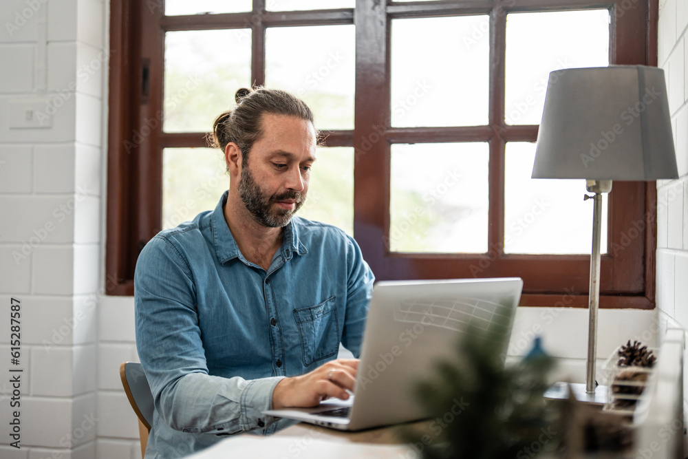 Caucasian handsome businessman typing on computer alone in house. 