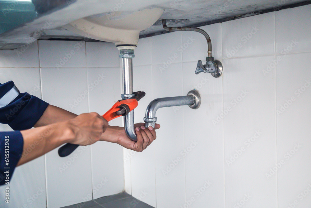 Plumber working in the bathroom, plumbing repair service, repairing leaking sinks with adjustable wr