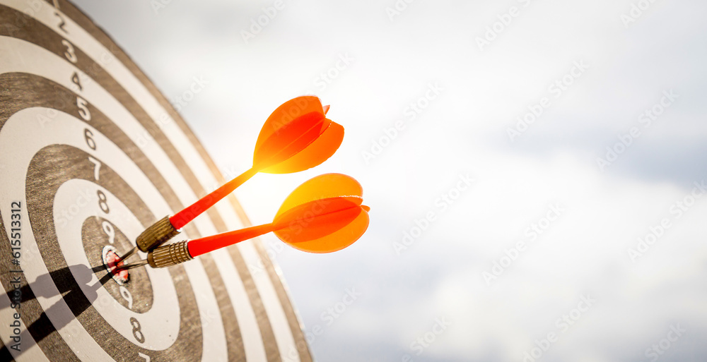 Close up shot red darts arrows in the target  of dartboard center on dark blue sky background. Busin