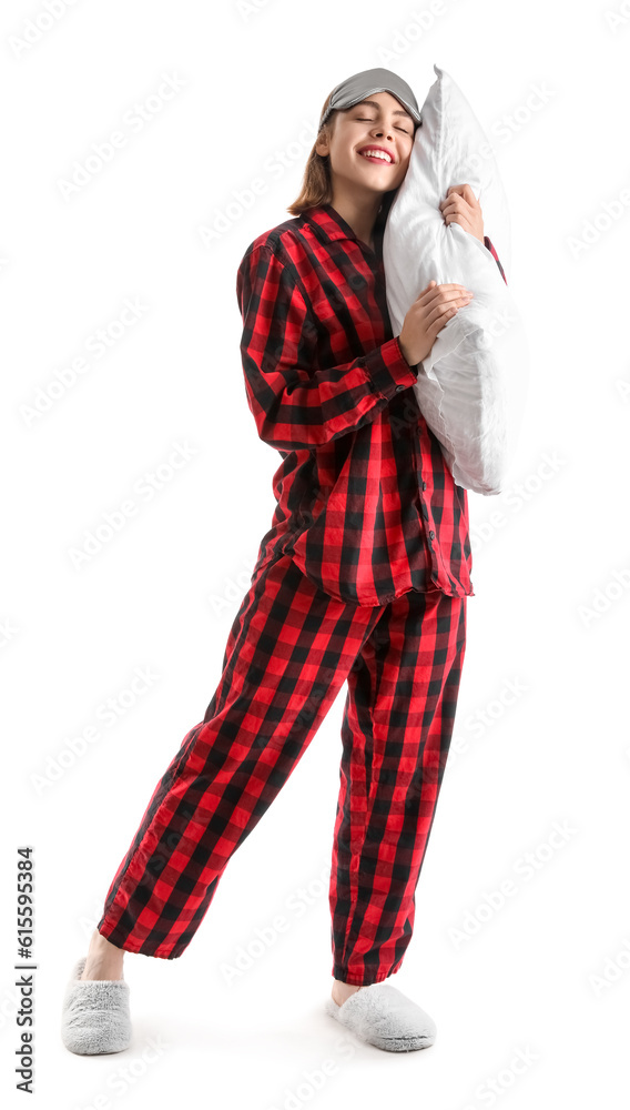 Young woman in checkered pajamas with pillow on white background