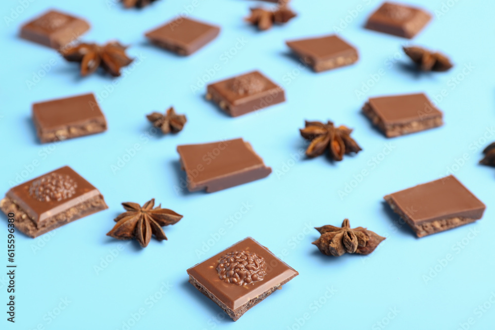 Composition with pieces of tasty chocolate and anise stars on color background, closeup