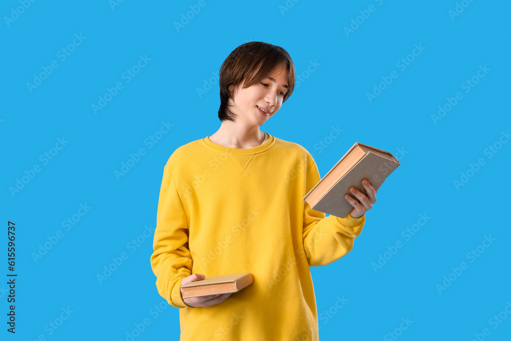 Teenage boy with books on blue background