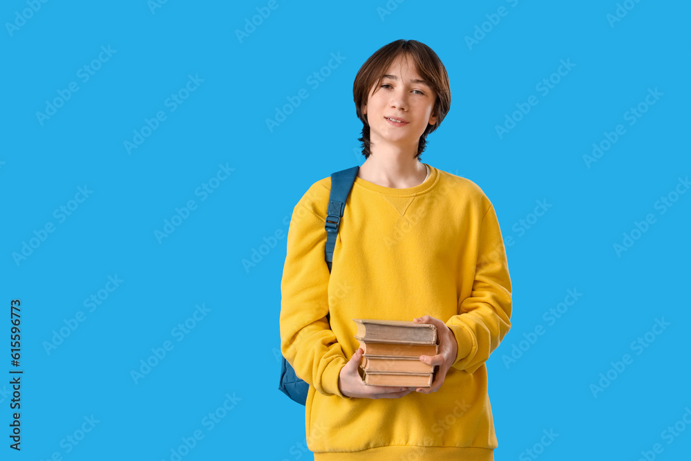 Teenage boy with books on blue background