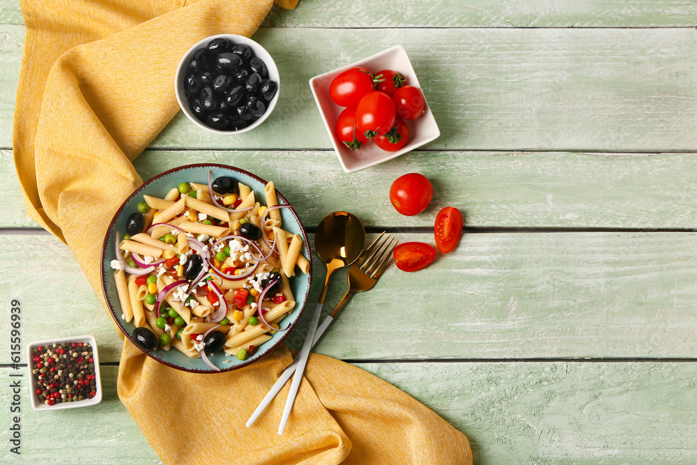 Bowl with tasty pasta salad and ingredients on light wooden background