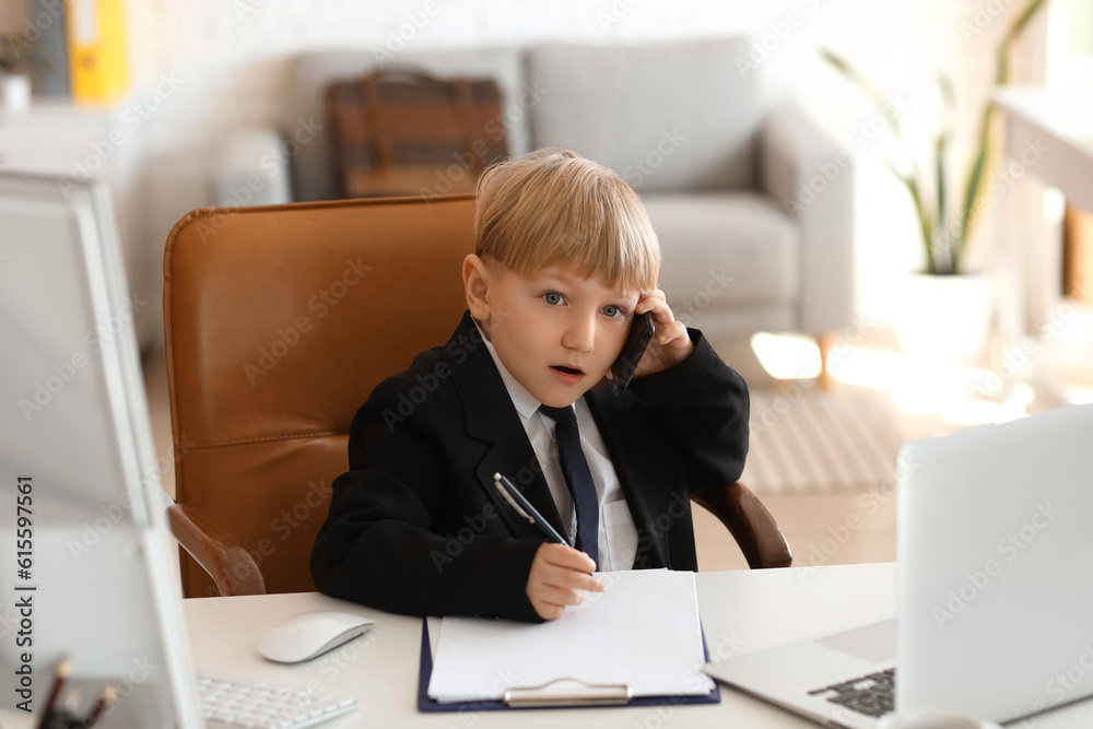 Funny little businessman talking by mobile phone at table in office