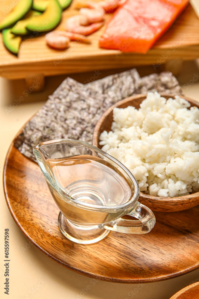 Plate with boiled rice, vinegar and nori sheets on color background, closeup