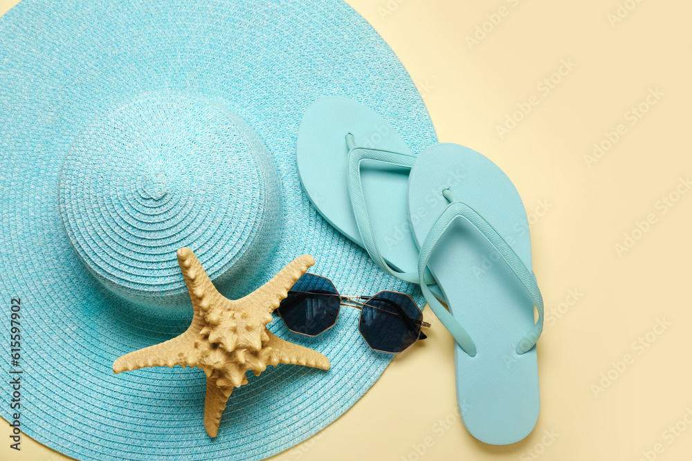 Flip-flops with sunglasses, starfish and hat on beige background