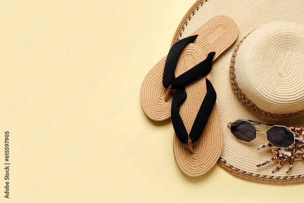 Flip-flops with sunglasses, seashell and hat on beige background