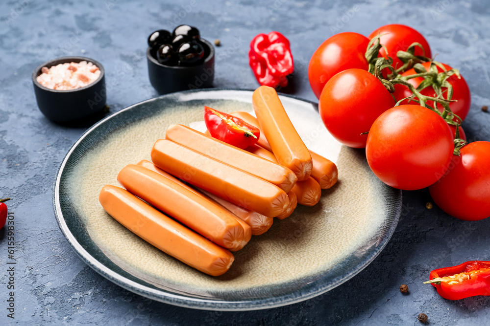 Plate with sausages, tomatoes and olives on blue background