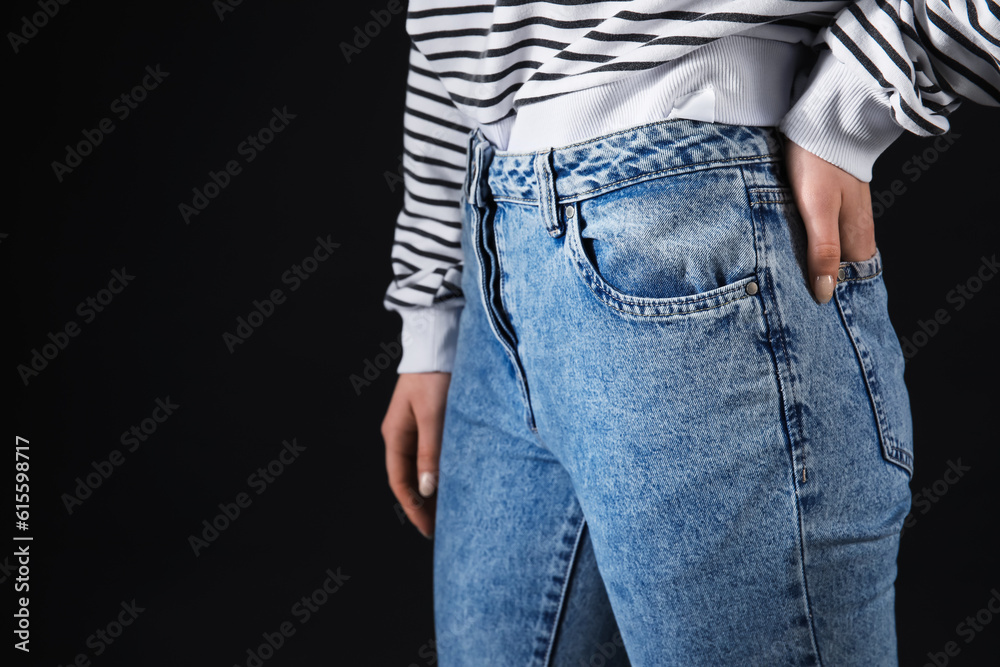 Young woman in stylish jeans on black background, closeup