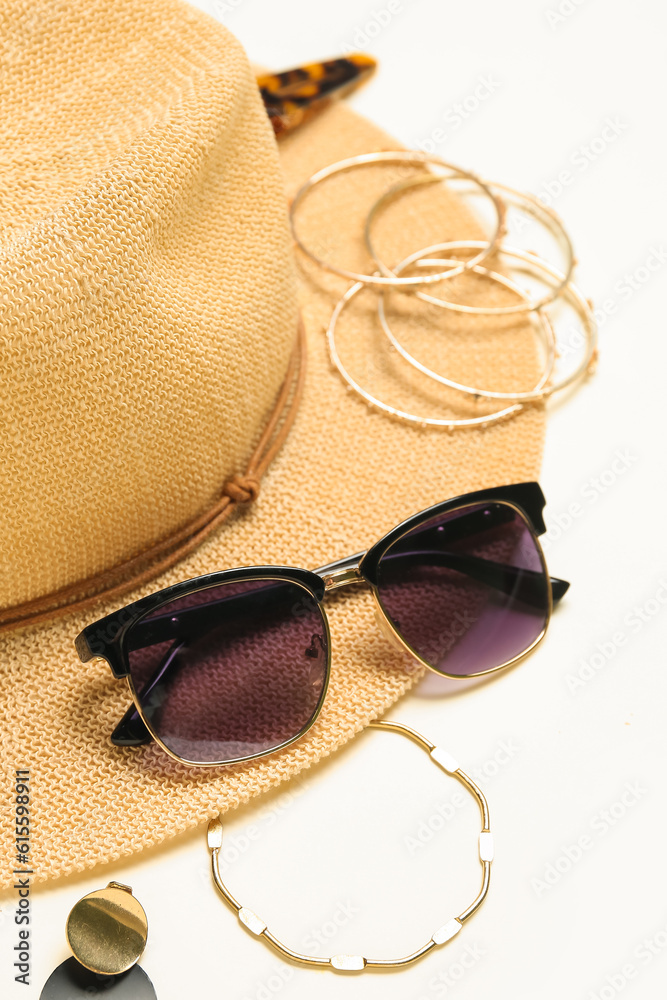 Stylish jewelry with sunglasses and summer hat on light background, closeup