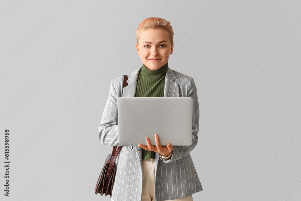 Female student using laptop on light background