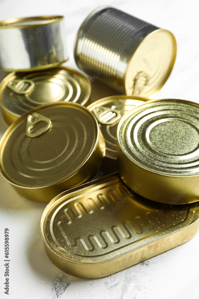 Different tin cans with fish on white marble table