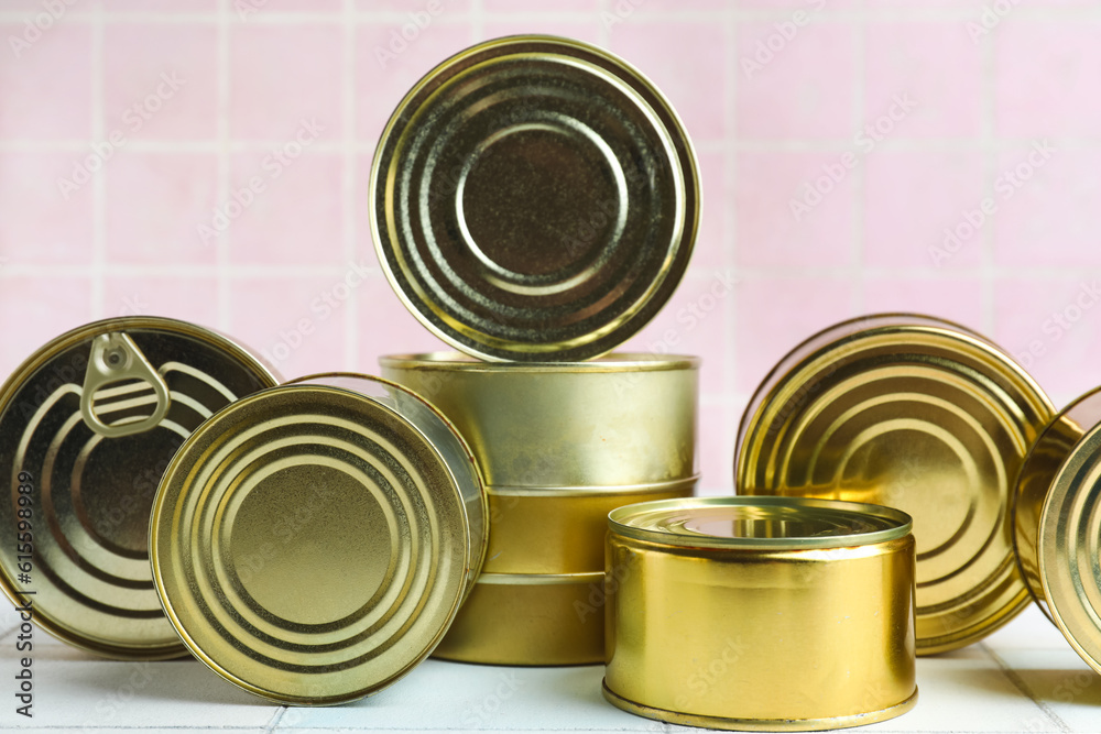 Tin cans with fish on white tiled table