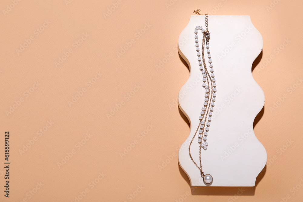 Showcase pedestal with golden necklaces on beige background