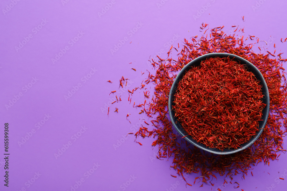 Bowl with pile of saffron on purple background