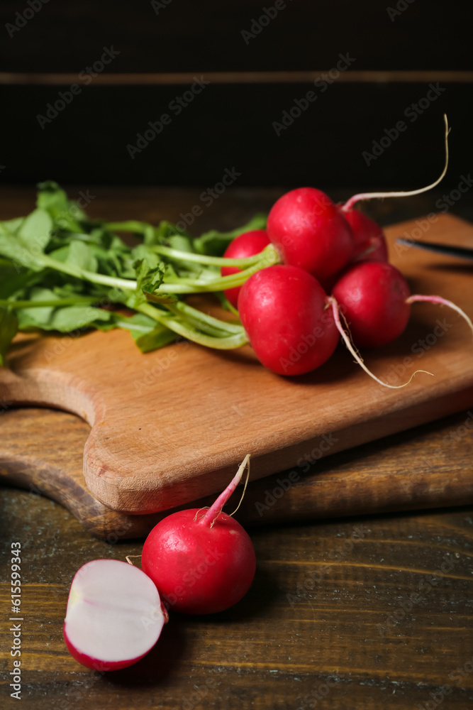 Wooden boards of ripe radish with green leaves on table