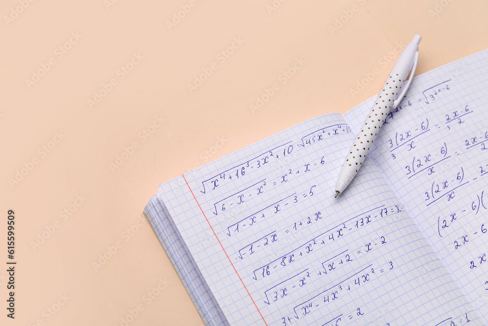 Copybook with maths formulas and pen on beige background