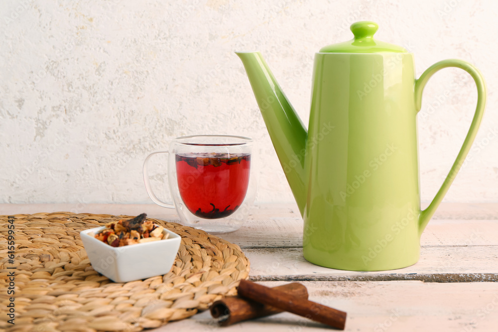 Wicker mat with teapot and cup of fruit tea on white wooden table